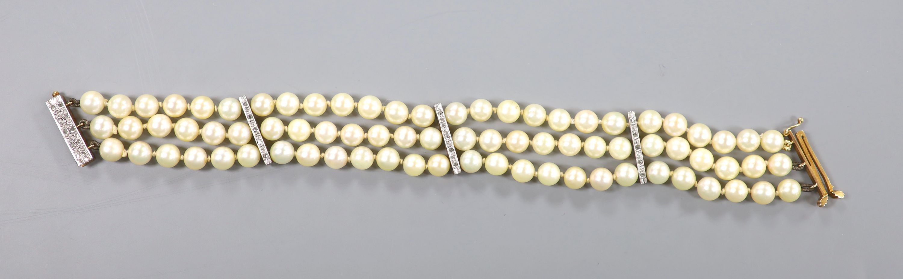 A triple strand cultured pearl bracelet, with yellow metal and diamond chip set spacers and clasp, 20.5cm, gross weight 34.2 grams, pearl diameter 6.4mm.